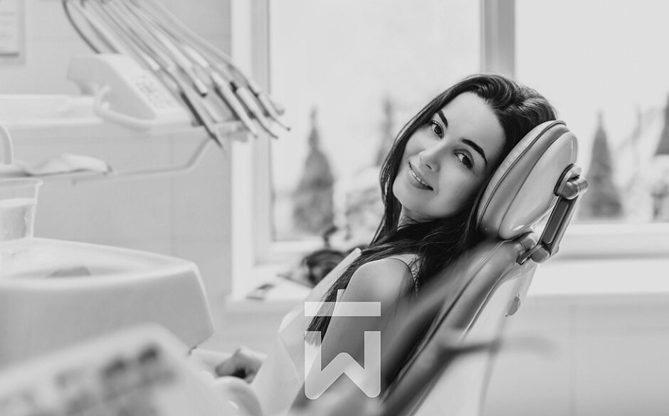 Eine junge, auf dem Behandlungsstuhl sitzende Angstpatientin schaut entspannt in die Kamera